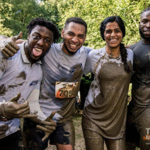 group of three black men and one indian woman covered in mud